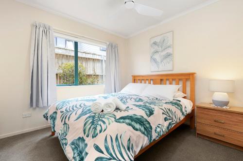 a bedroom with a bed with two towels on it at Mount Sunset - Mt Maunganui Townhouse in Mount Maunganui