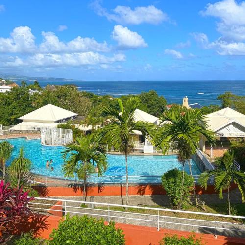 an aerial view of a resort swimming pool with palm trees at Résidence La Baie 1 Océane in La Trinité