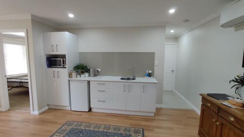 uma cozinha com armários brancos e um lavatório em Se-Ayr BnB at Lighthouse em Port Macquarie