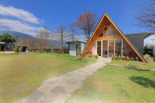 a house with a triangular roof on a grass field at Jiang's B&B 江院子庭園民宿 in Jian
