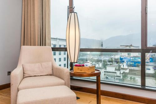 a living room with a chair and a large window at Fliport Garden Hotel Wuyishan in Wuyishan