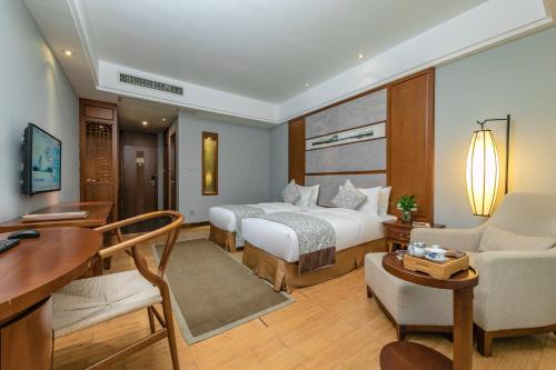 a hotel room with two beds and a desk at Fliport Garden Hotel Wuyishan in Wuyishan