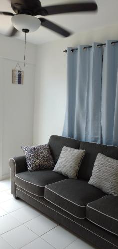 a black couch in a living room with a ceiling fan at Mar Bonita Beach Appartment II in Isabela