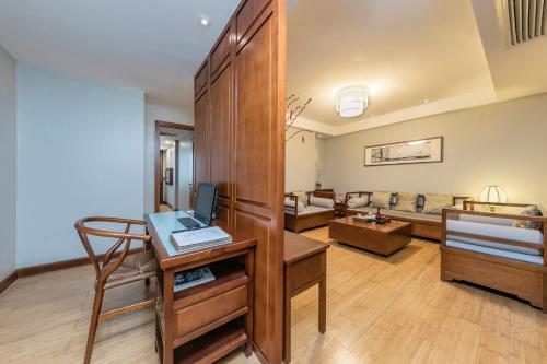 a living room with a desk and a couch at Fliport Garden Hotel Wuyishan in Wuyishan