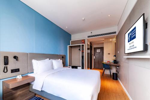 a bedroom with a large white bed and a desk at Holiday Inn Express Shanghai Baoyang by IHG in Baoshan