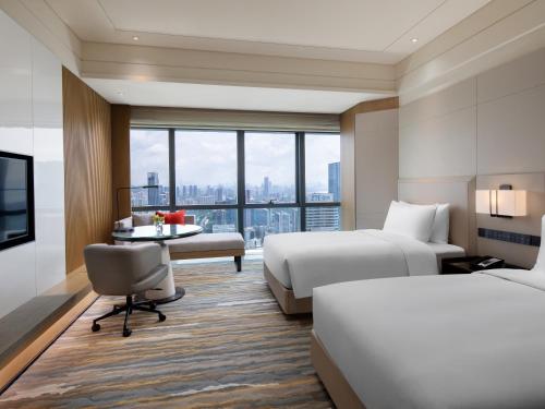 a hotel room with two beds and a desk and a tv at Crowne Plaza Shenzhen Nanshan by IHG in Shenzhen