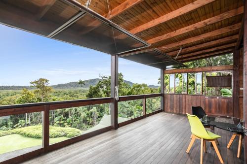 a view from the balcony of a house with a table and yellow chairs at Daintree Holiday Homes - La Vista in Cow Bay