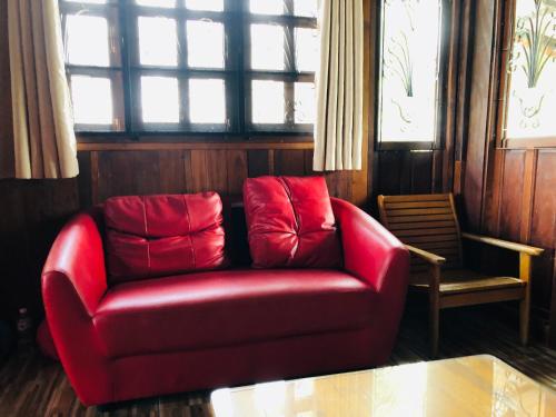 a red couch sitting in a room with a window at Mekong Tarawadee Villa in Tha Bo