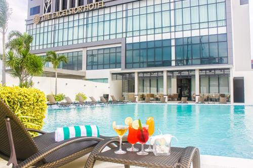 a table with two glasses of wine next to a swimming pool at The Excelsior Hotel Las Piñas in Manila