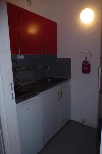 a kitchen with a sink and red cabinets at Larnica in Le Corbier