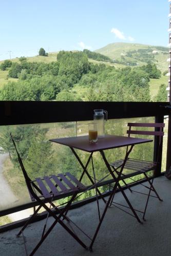 a table and two chairs on a balcony with a view at Larnica in Le Corbier