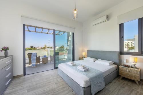 a bedroom with a large bed and a balcony at Pernera Beach Villa in Protaras