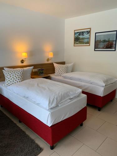 two beds in a bedroom with two lamps on the wall at Landhaus am Schaalsee in Zarrentin