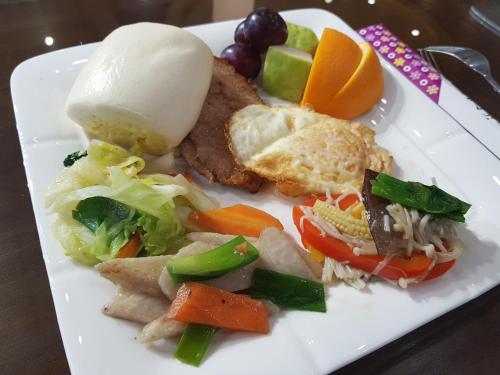 un plato blanco de comida con verduras y carne en Tomi House, en Hengshan