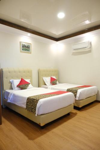 two beds in a bedroom with white walls and wood floors at Joyful Hotel in Tanjungpandan