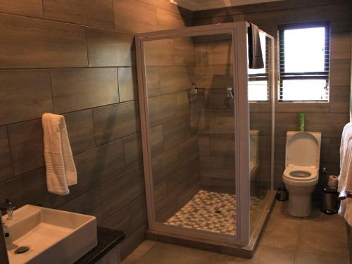 a bathroom with a shower with a toilet and a sink at Nkonyeni Lodge & Golf Estate in Ngwempisi