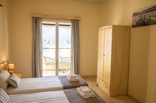 a bedroom with a bed and a large window at SunRose Beach Aparthotel in Acharavi