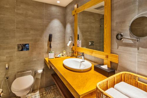 ein Badezimmer mit einem Waschbecken, einem WC und einem Spiegel in der Unterkunft Swosti Chilika Resort in Kānāipur