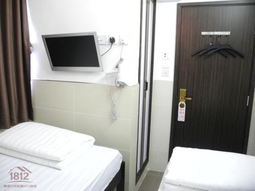 香港的住宿－九龍旺角1812賓館，小房间设有两张床和一台墙上的电视