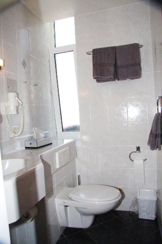a white bathroom with a toilet and a sink at Stichwehs Hotel am Bahnhof in Elze