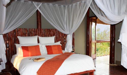 a bedroom with a bed with orange and white pillows at Zwahili Private Game Lodge & Spa in Modimolle