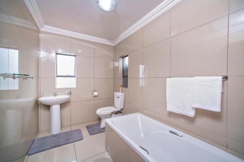 y baño con bañera, aseo y lavamanos. en Khayalami Hotel - Emalahleni, en Witbank