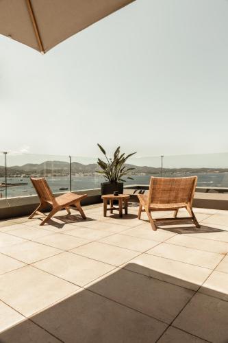 two chairs and a table on a patio with a view of the ocean at OKU Ibiza in San Antonio