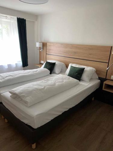 a bedroom with two beds with white sheets and green pillows at Ramspauer Hof in Regenstauf