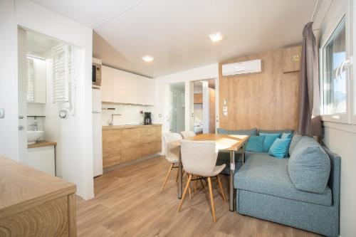 a living room and kitchen with a blue couch and a table at Camping Inntal in Wiesing