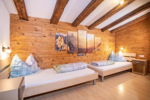 two beds in a room with wooden walls at Camping Inntal in Wiesing