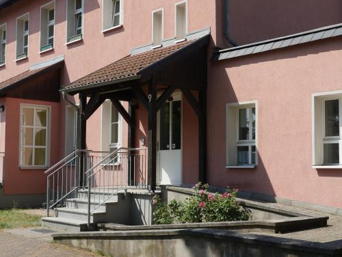 a pink building with a porch and stairs in front at Touristisches Begegnungzentrum Melchow in Melchow