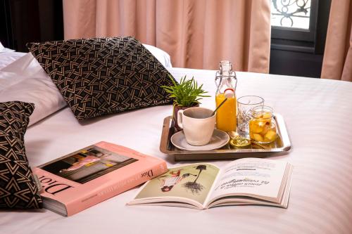 a tray with a book and a drink on a bed at First Hotel Paris Tour Eiffel in Paris