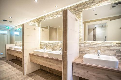 a bathroom with three sinks and two mirrors at Camping Inntal in Wiesing