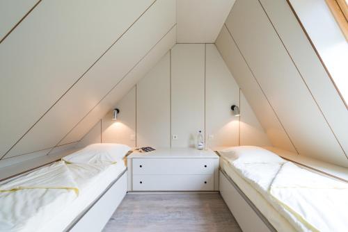2 bedden in een zolderslaapkamer met witte muren bij Zentrum Worriken Holiday Cottages in Butgenbach