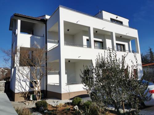 a white building with trees in front of it at Apartmani Nika in Rijeka