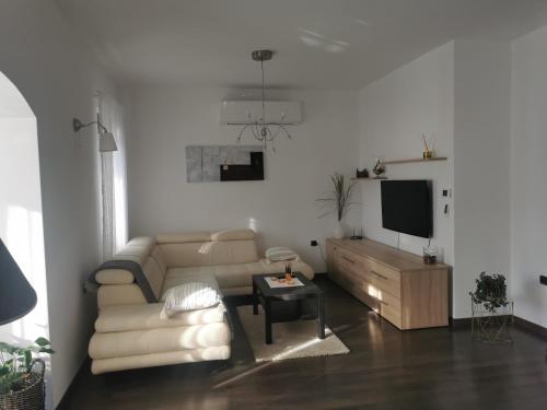 a white living room with a couch and a tv at Apartmani Nika in Rijeka