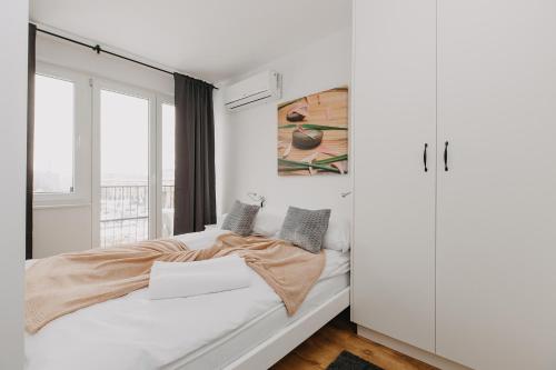 a white bedroom with a bed and a window at ShortStayPoland Pańska in Warsaw