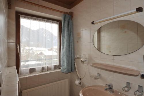 La salle de bains est pourvue d'un lavabo, d'un miroir et d'une fenêtre. dans l'établissement Salzburgerhof Jugend- und Familienhotel, à Lofer