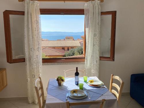 una mesa con una botella de vino y una ventana en Tanca della Torre Trilocale vista mare, en Isola Rossa