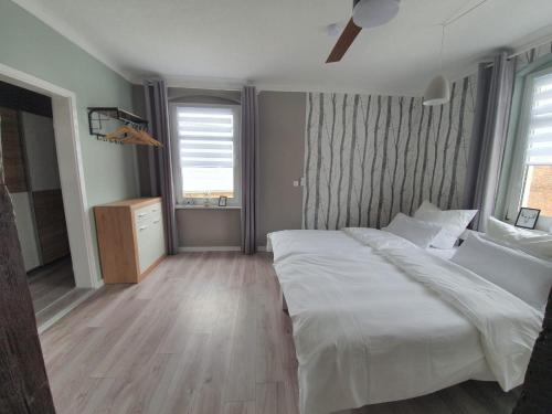 a bedroom with a large white bed and two windows at Haus Kabelitz in Kabelitz