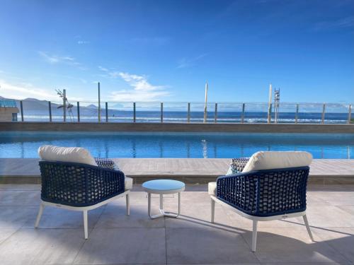 dos sillas y una mesa frente a una piscina en Hotel Cristina by Tigotan Las Palmas - Adults Only, en Las Palmas de Gran Canaria