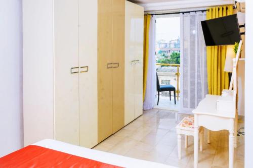 a bedroom with a bed and a desk and a television at RÉSIDENCE DOLCE VITA - BONANJO in Douala