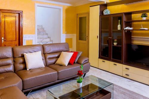 a living room with a brown couch and a tv at RÉSIDENCE DOLCE VITA - BONANJO in Douala