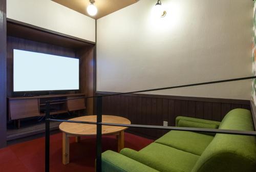 Cette chambre dispose d'une télévision, d'un canapé et d'une table. dans l'établissement Ikaho Syusuien, à Shibukawa