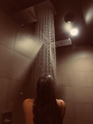 a person is standing in a shower with water pouring from the ceiling at Octavie - Suite de luxe à Tournai avec piscine privée, jacuzzi, sauna et hammam in Tournai
