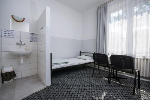 a bathroom with two chairs and a sink and a window at Noclegi PODZAMCZE PTTK in Przemyśl