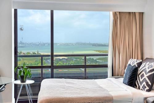 a bedroom with a bed and a large window at Sea and City Views Takapuna Studio - Free Carpark in Auckland