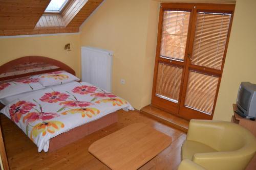 a bedroom with a bed and a chair and a television at Ubytovanie Marta Kováčová in Bešeňová