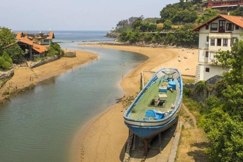 a boat sitting on the shore of a beach at Piso en Lekeitio, Costa Vasca, Bizkaia. in Lekeitio