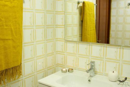 y baño con lavabo, espejo y toalla amarilla. en Piso en Lekeitio, Costa Vasca, Bizkaia., en Lekeitio